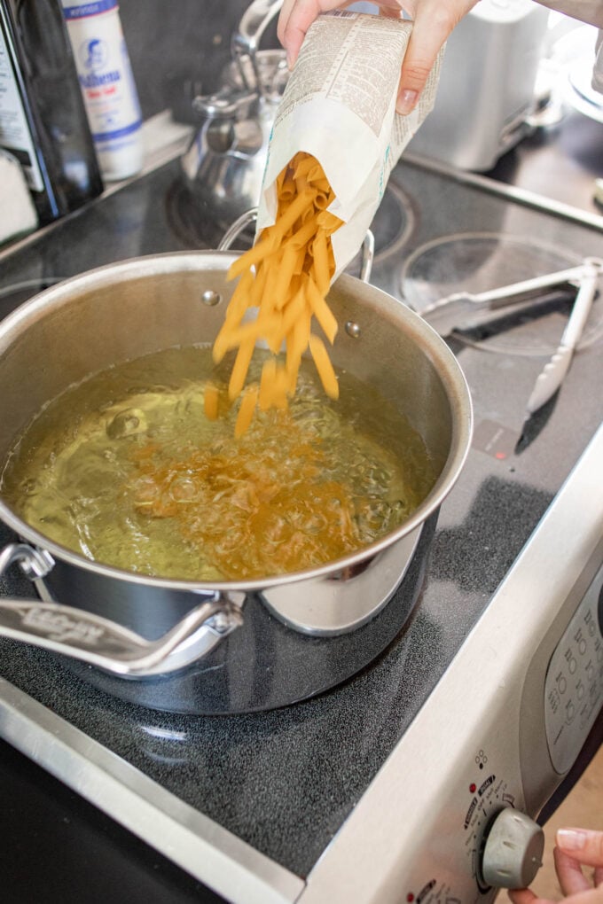 hand pouring pasta into pot