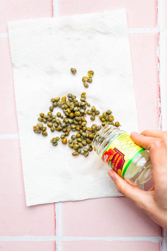 hand pouring capers onto paper towel