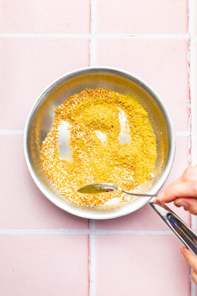 hand stirring toasted bread crumbs in pan