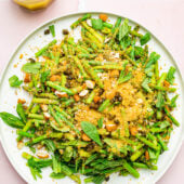 cold asparagus salad on white plate with dressing in jar